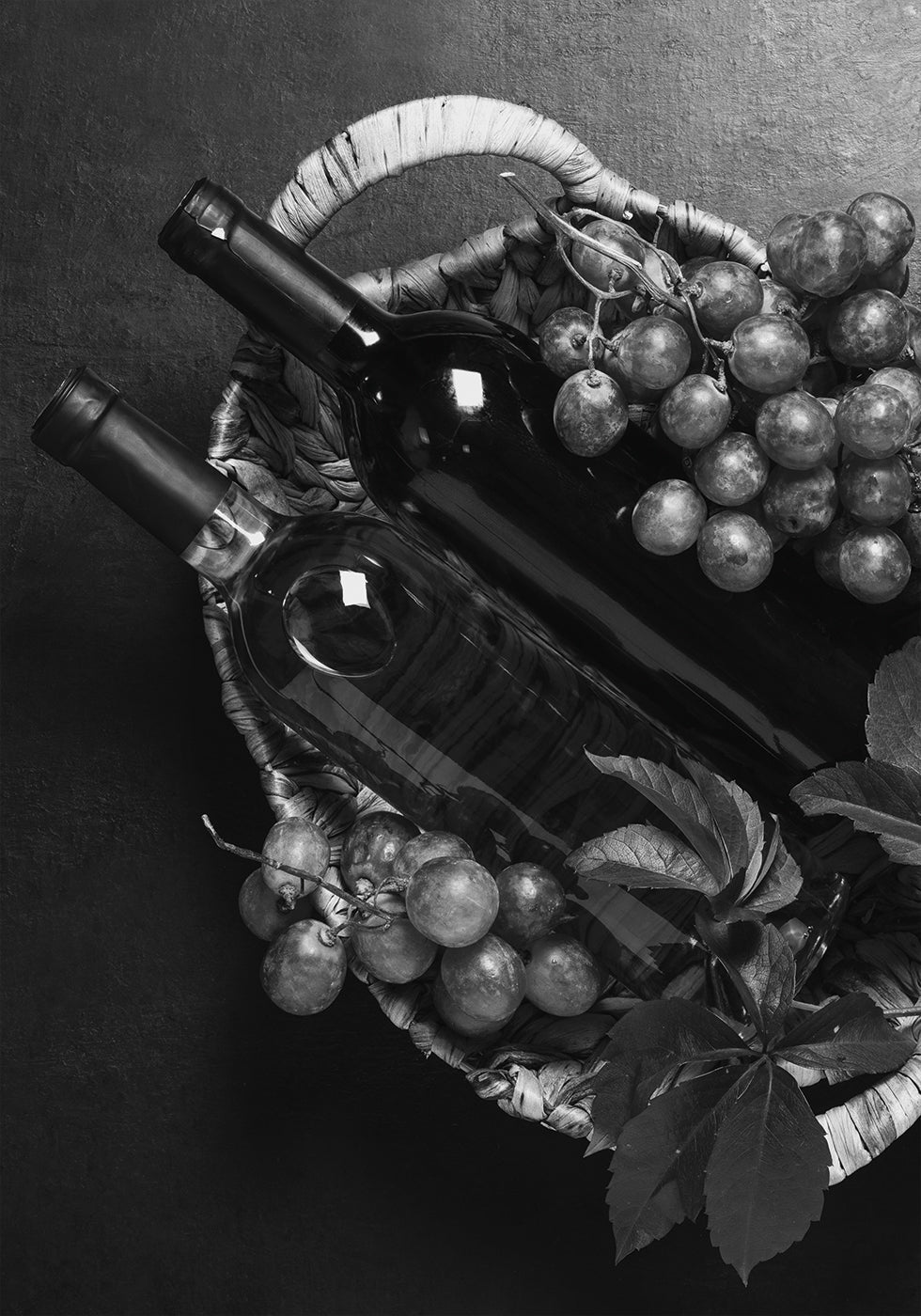 a basket of grapes and a bottle of wine